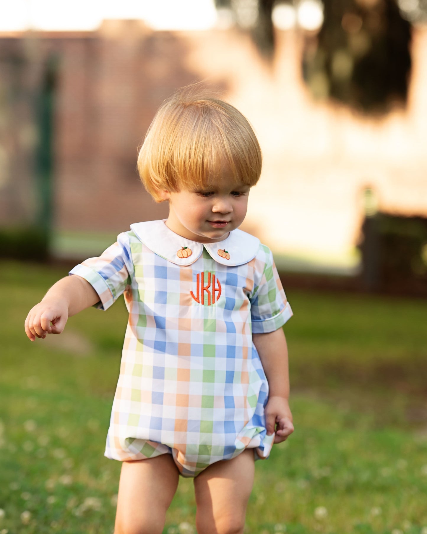 Child wearing a colorful checkered outfit with a collar in an outdoor setting