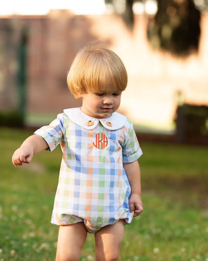 Child wearing a colorful checkered outfit with a collar in an outdoor setting