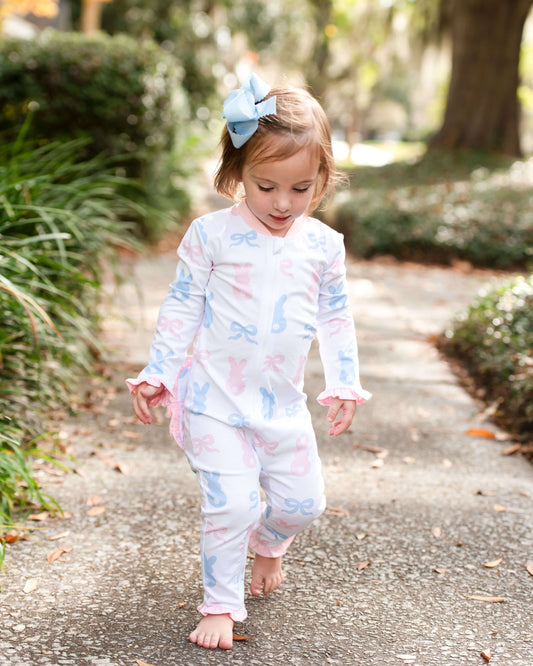 Child wearing a colorful outfit with bows outdoors on a path.