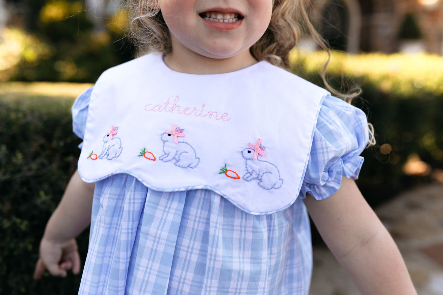 Child wearing a dress with embroidered designs and text outdoors