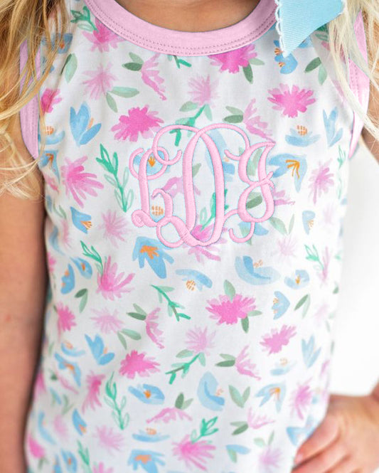 Child wearing a floral-patterned shirt with pink monogram initials