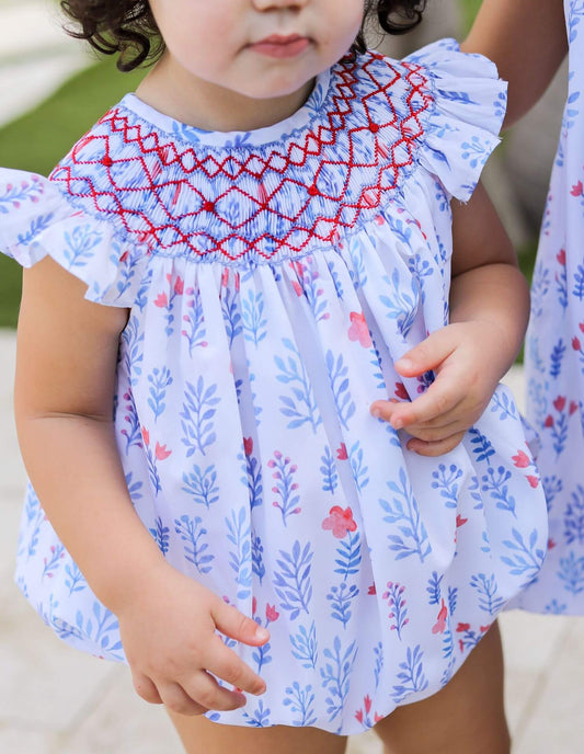 Child wearing a floral dress with red embroidery details