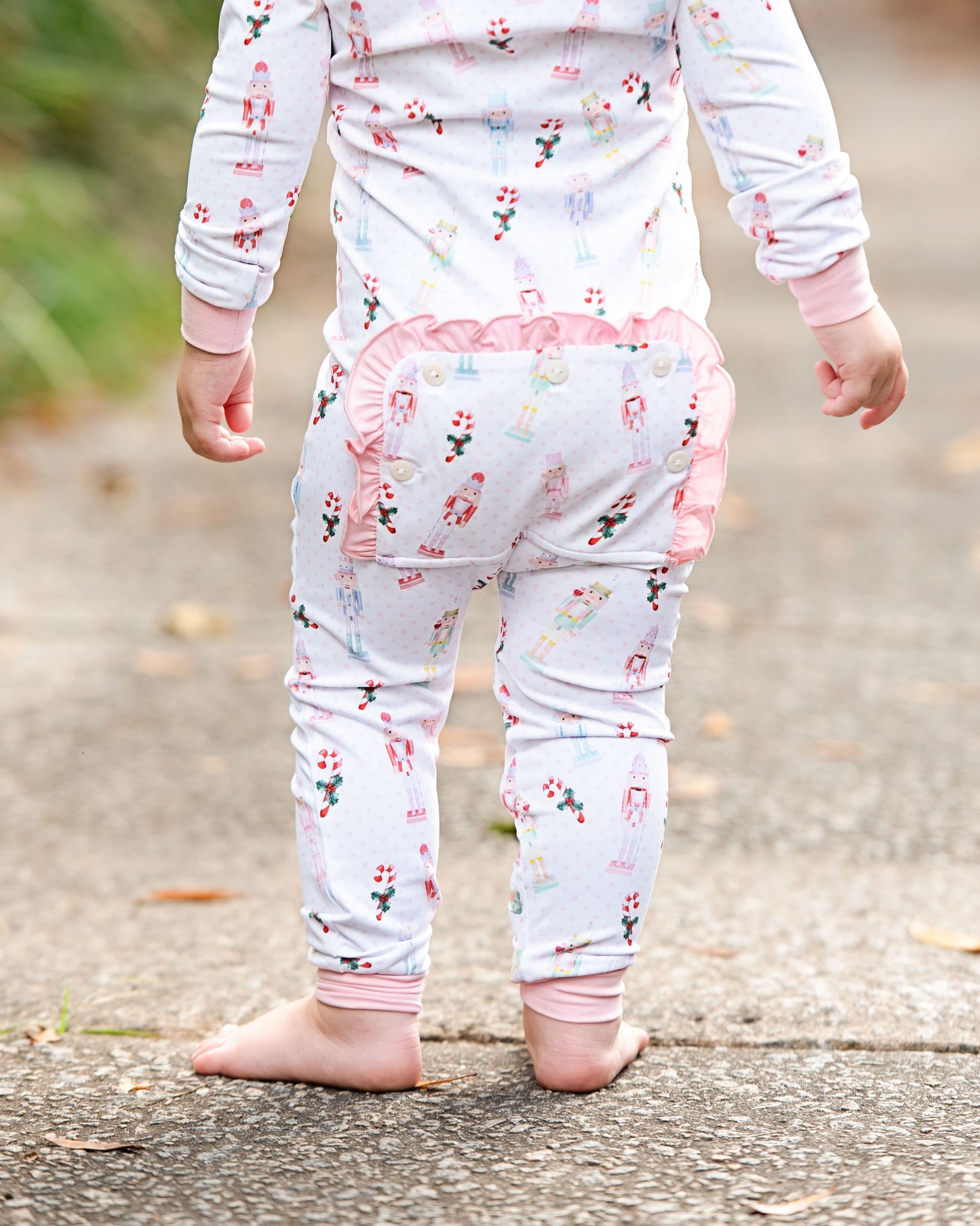 Child wearing a floral outfit with pink accents on a blurred outdoor background