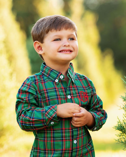 Child wearing a green plaid shirt with a monogram in a natural setting