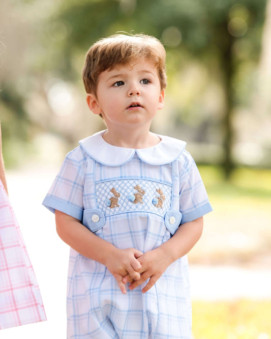 Child wearing a light blue bubble with embroidered details outdoors