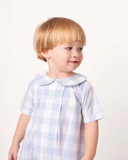 Child wearing a light blue checkered dress with a collar on a white background