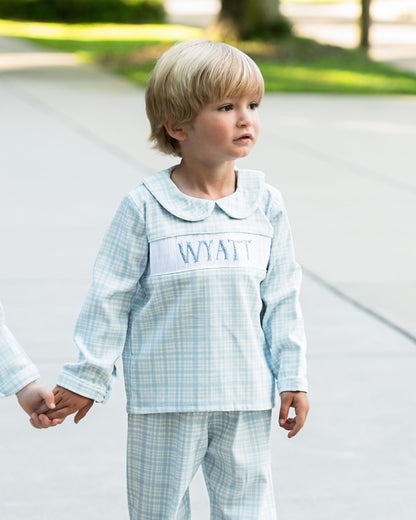 Child wearing a light blue checkered outfit with 'Wyatt' embroidered on the chest, standing outdoors.