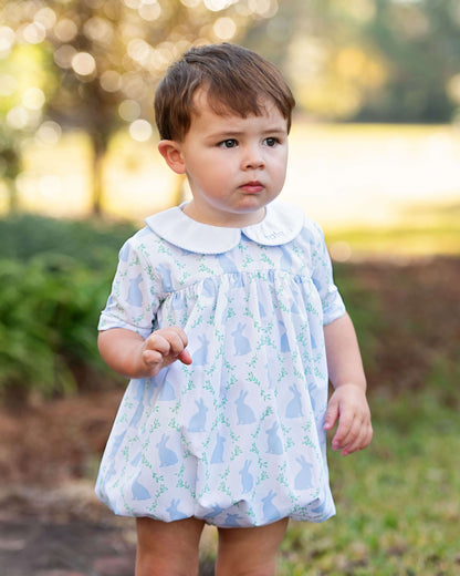 Child wearing a light blue dress with a floral pattern outdoors