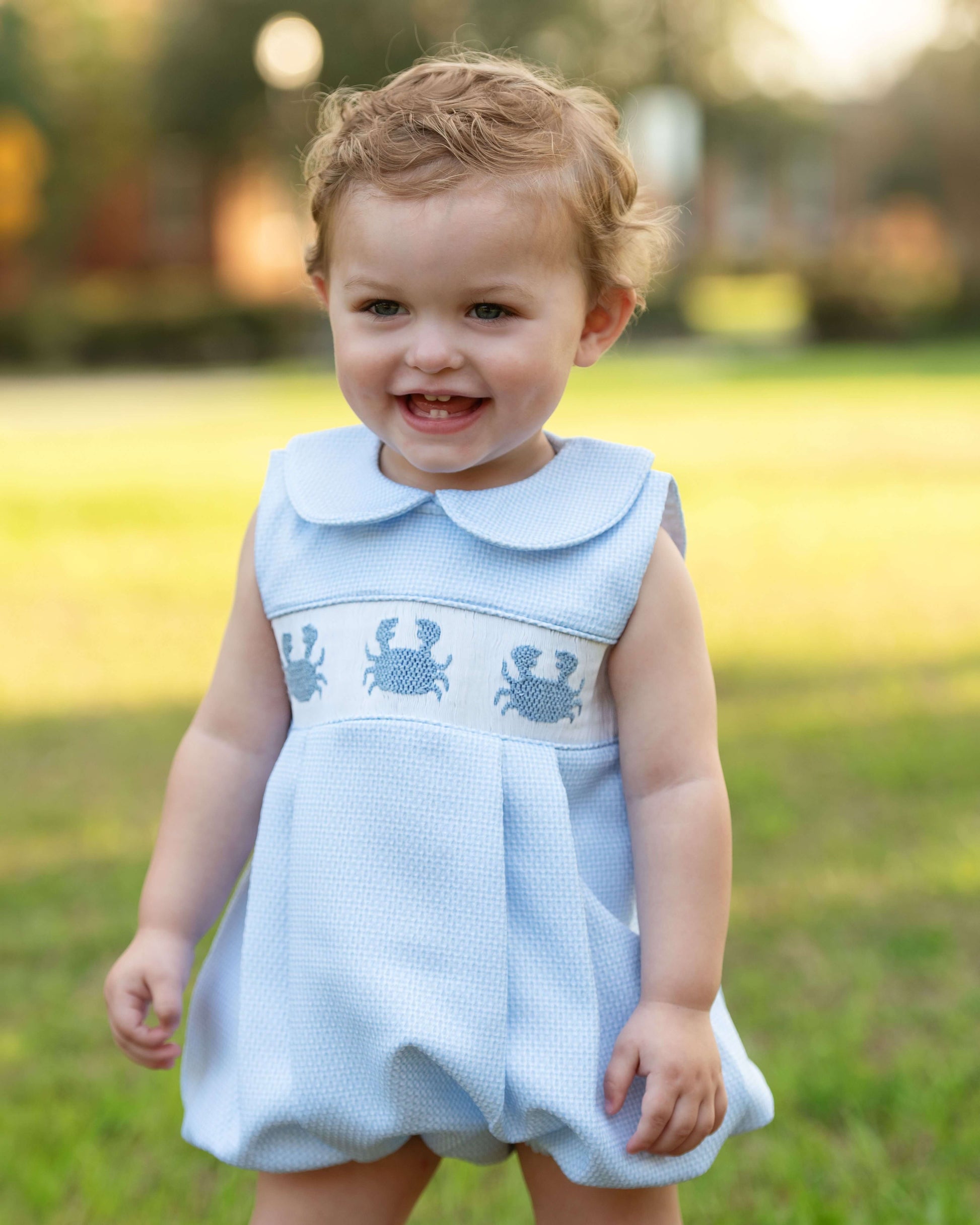 Child wearing a light blue dress with crab patterns outdoors