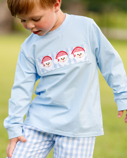 Child wearing a light blue long-sleeve shirt with a snowman design on a grassy background