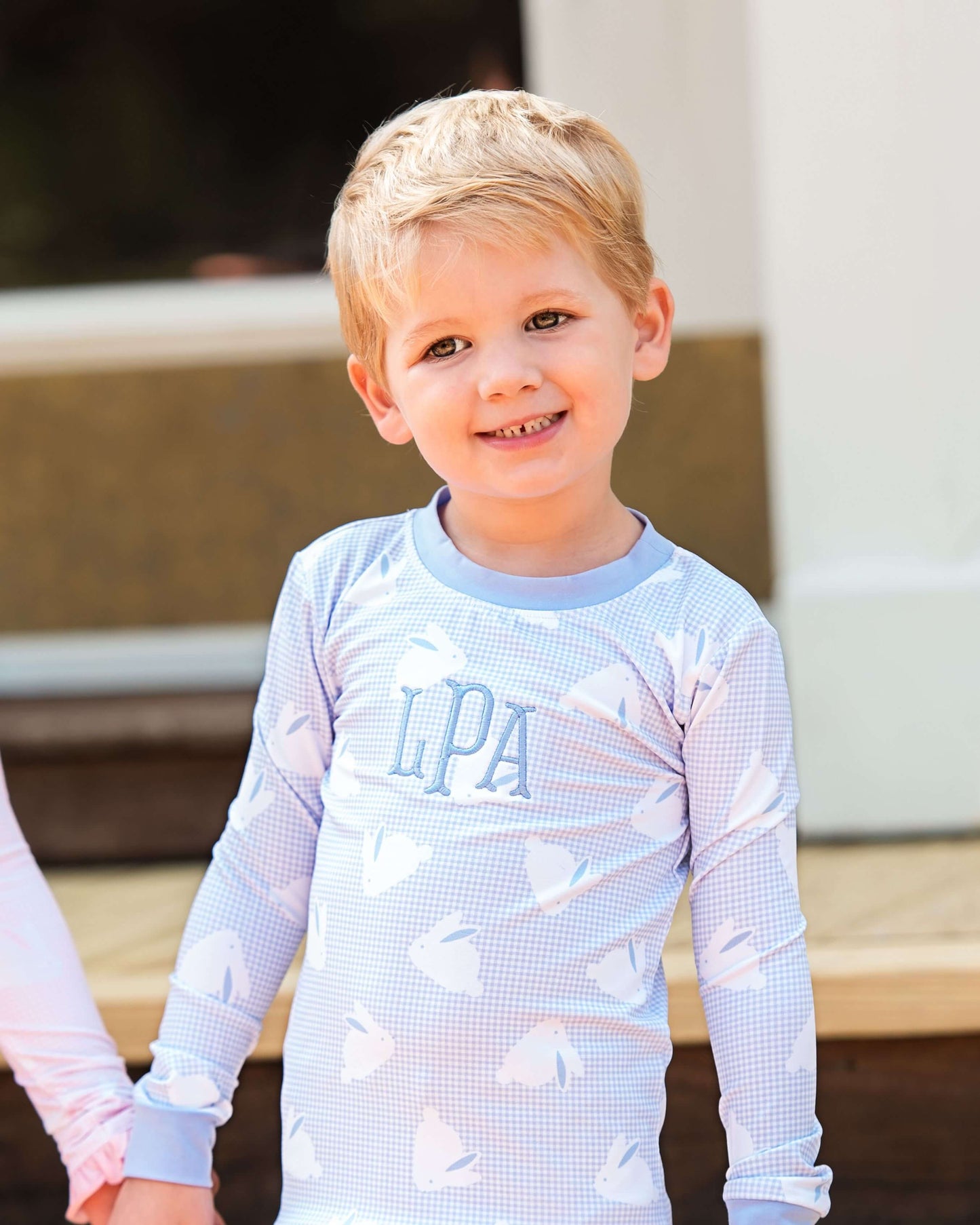Child wearing a light blue long-sleeve shirt with heart patterns and 'LPA' branding.