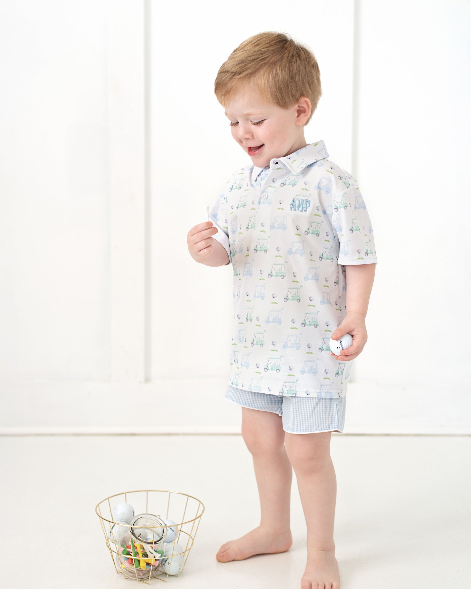 Child wearing a light blue outfit with a pattern, standing on a white background