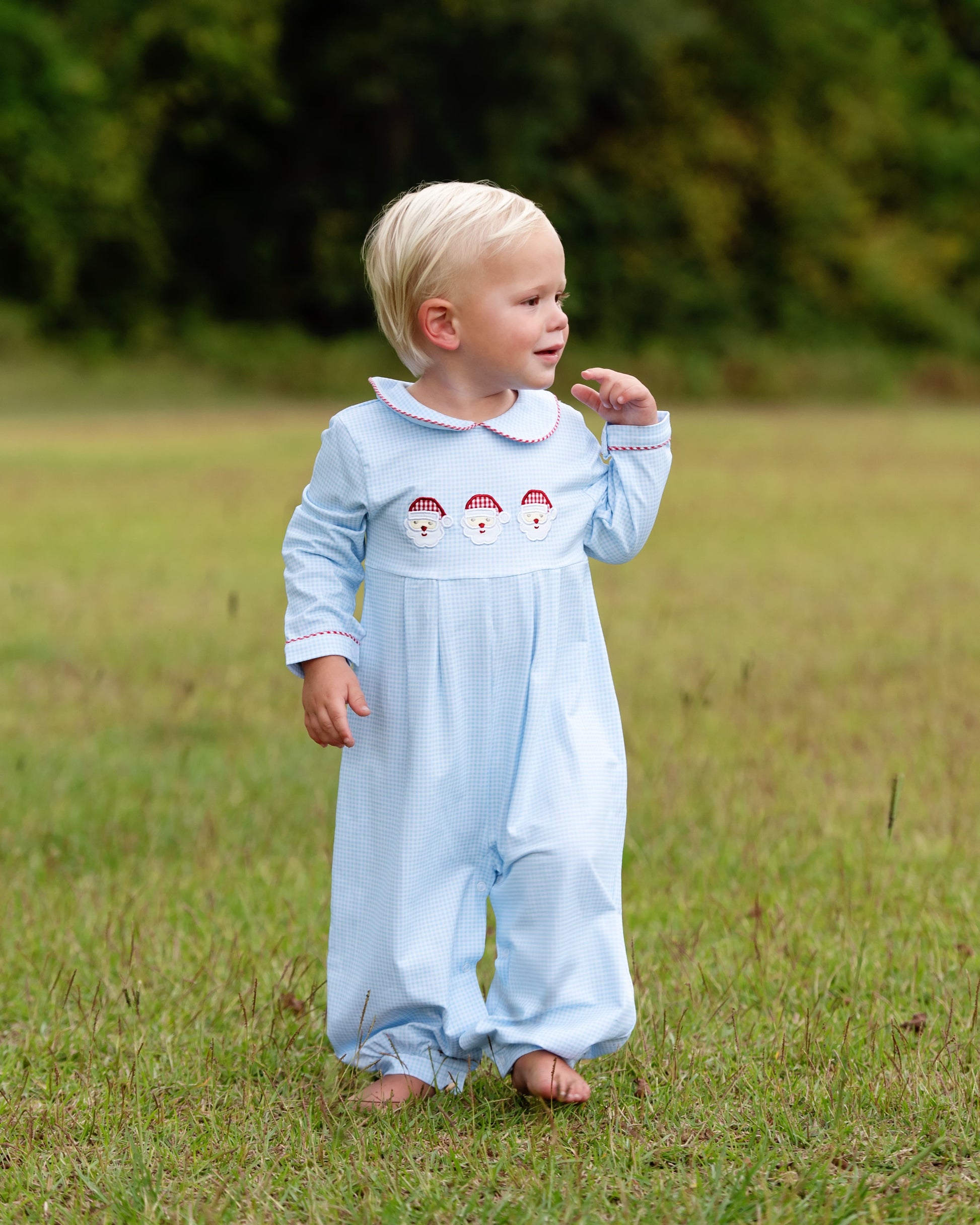 Child wearing a light blue outfit with embroidered designs in a grassy field