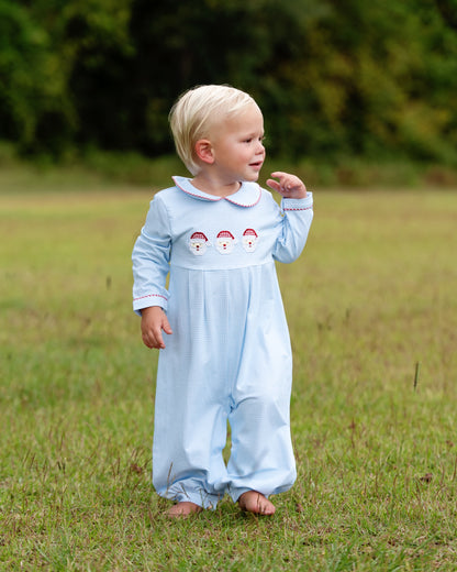 Child wearing a light blue outfit with embroidered designs in a grassy field