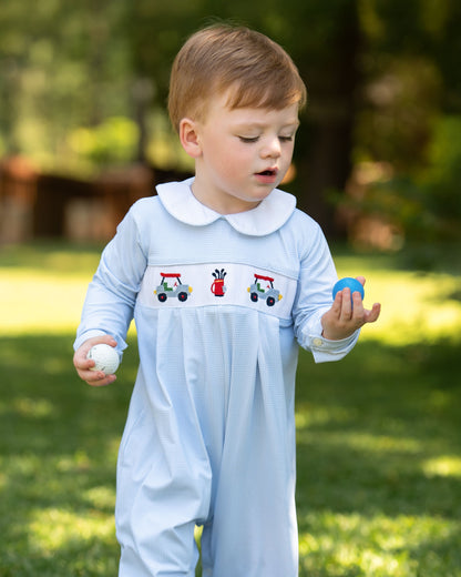 Child wearing a light blue outfit with embroidered designs outdoors on a grassy area