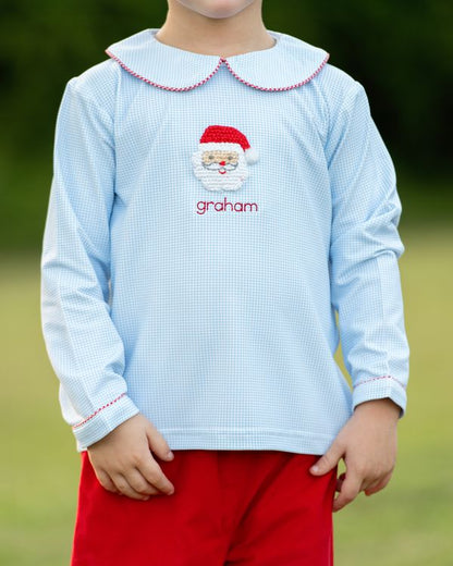 Child wearing a light blue shirt with a Santa face and 'graham' text, standing outdoors.
