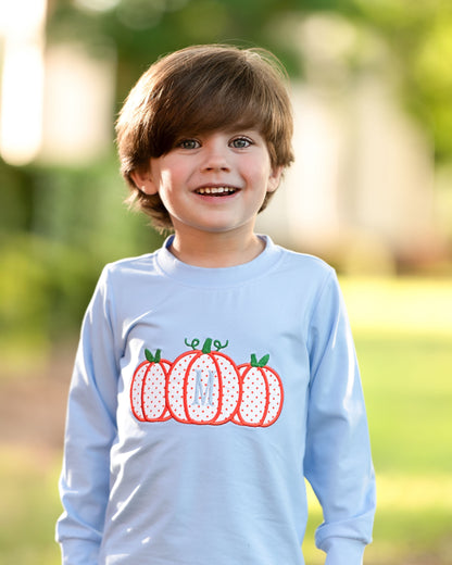 Child wearing a light blue shirt with pumpkin design outdoors
