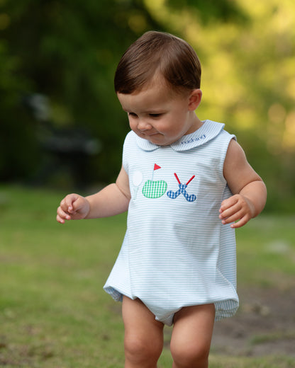 Child wearing a light blue sleeveless dress with a golf-themed design outdoors.