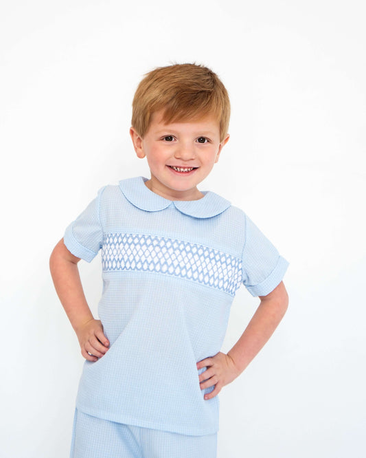 Child wearing a light blue smocked outfit on a white background