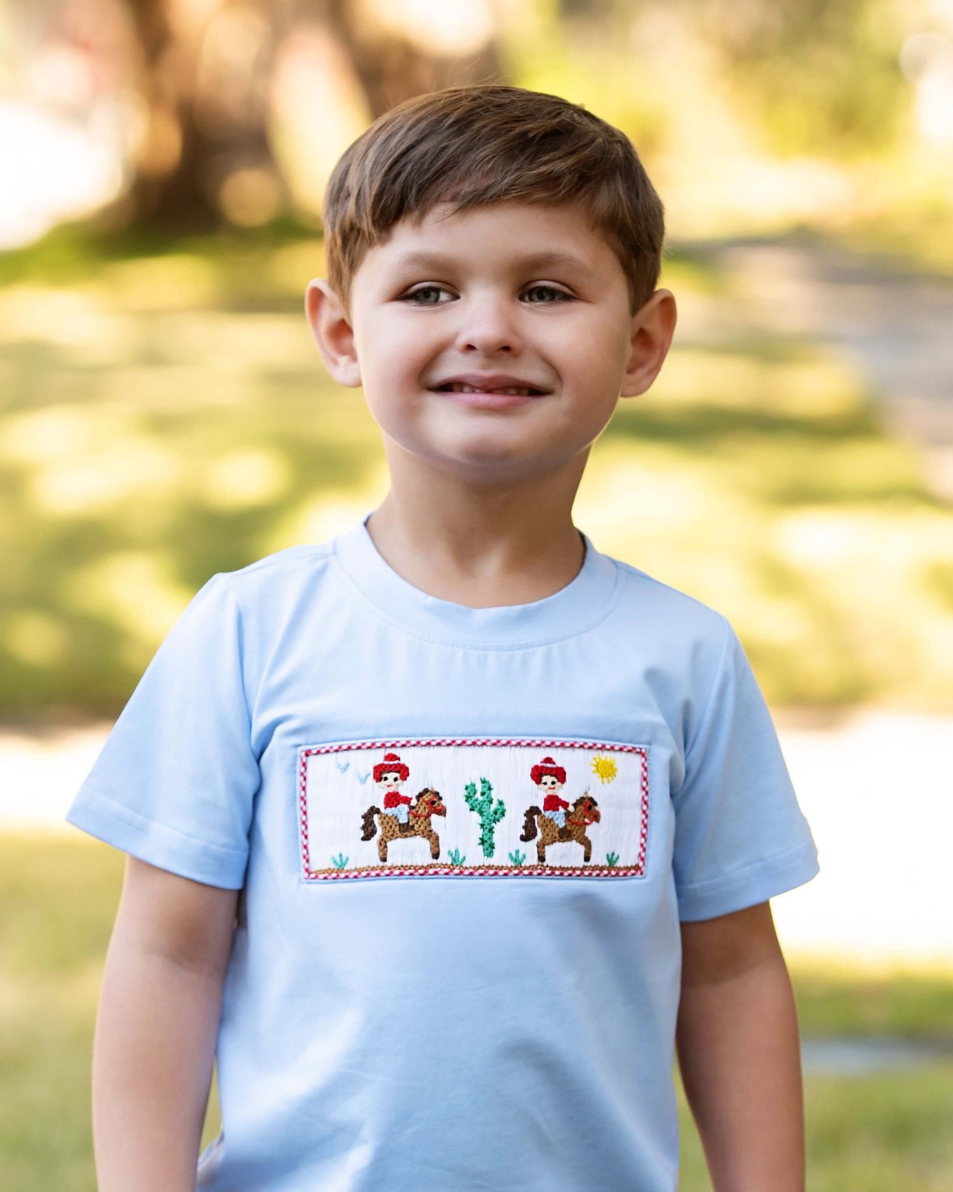 Child wearing a light blue t-shirt with a colorful design outdoors