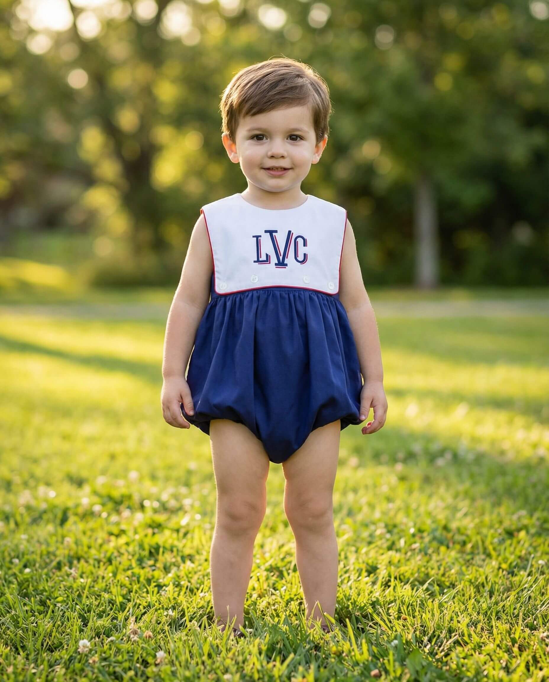 Child wearing a navy and white dress with 'LVC' initials standing on grass.