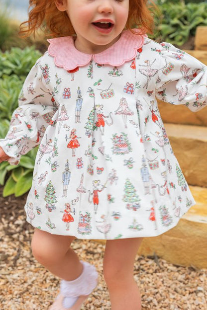 Child wearing a patterned dress with a pink collar outdoors