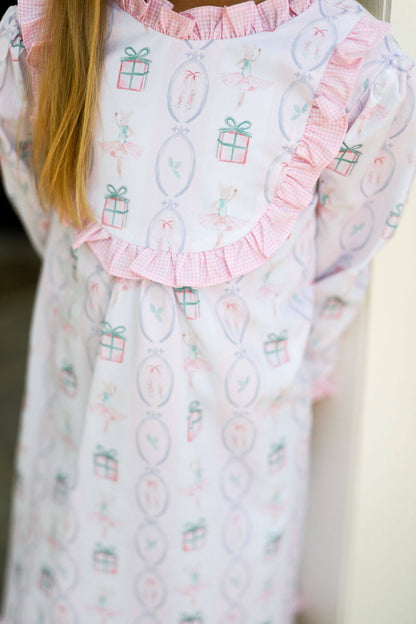 Child wearing a patterned holiday dress with ruffled collar and sleeves.