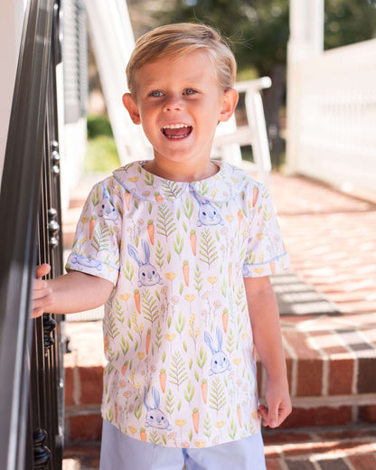 Child wearing a patterned shirt with bunnies and leaves outdoors