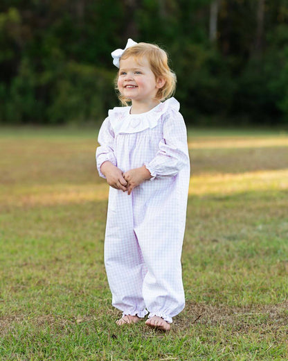 Child wearing a pink and white outfit with a bow in a grassy field