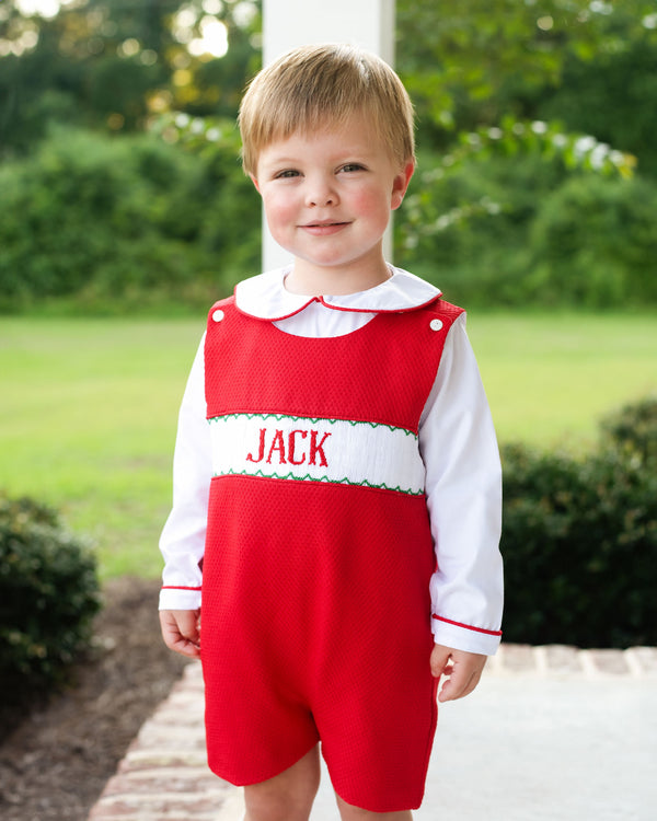 Child wearing a red custom smocked short romper set personalized with a name
