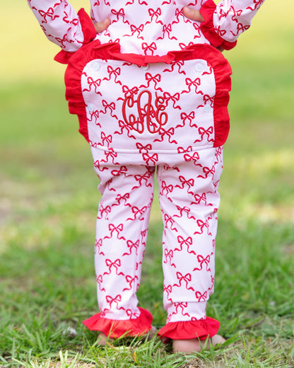 Child wearing a red and white outfit with bow pattern and 'CJ' monogram on grass