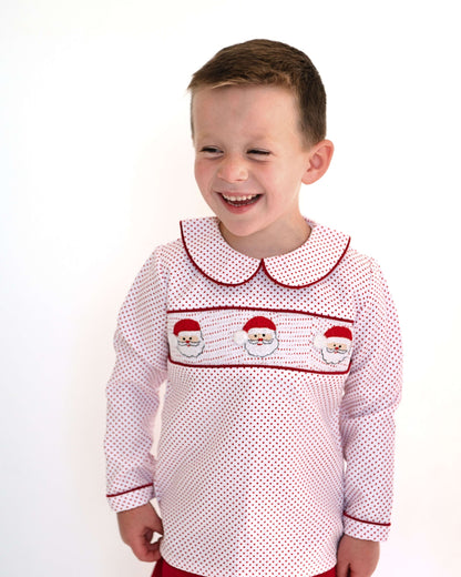 Child wearing a red and white patterned dress with embroidered details on a white background