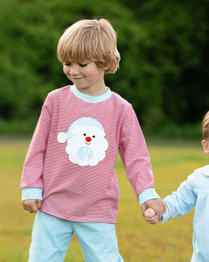 Child wearing a red and white striped shirt with a snowman design, standing outdoors.