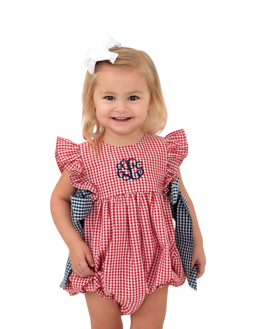Child wearing a red checkered romper with a monogram on a white background