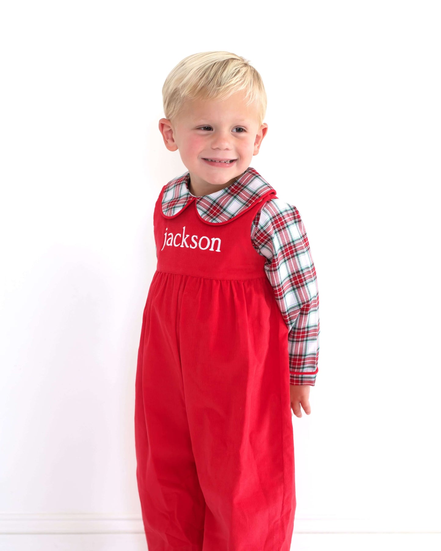 Child wearing a red dress with 'jackson' printed on it, standing against a white background