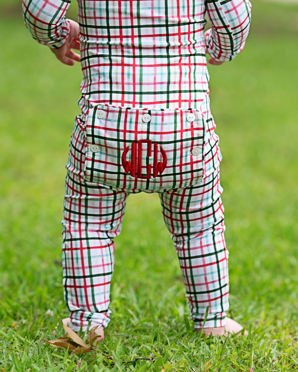 Child in red and green plaid windowpane with a bear design on grass