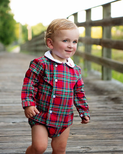 Child wearing a red plaid outfit on a wooden deck