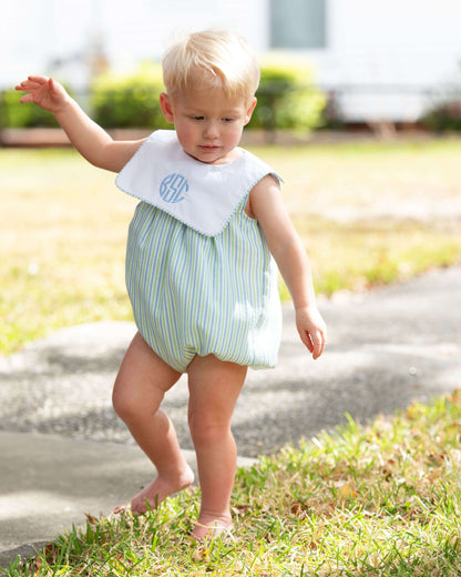 Child wearing a striped romper with a bib outdoors