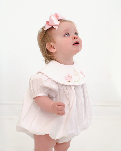 Child wearing a white dress with a pink bow on a white background