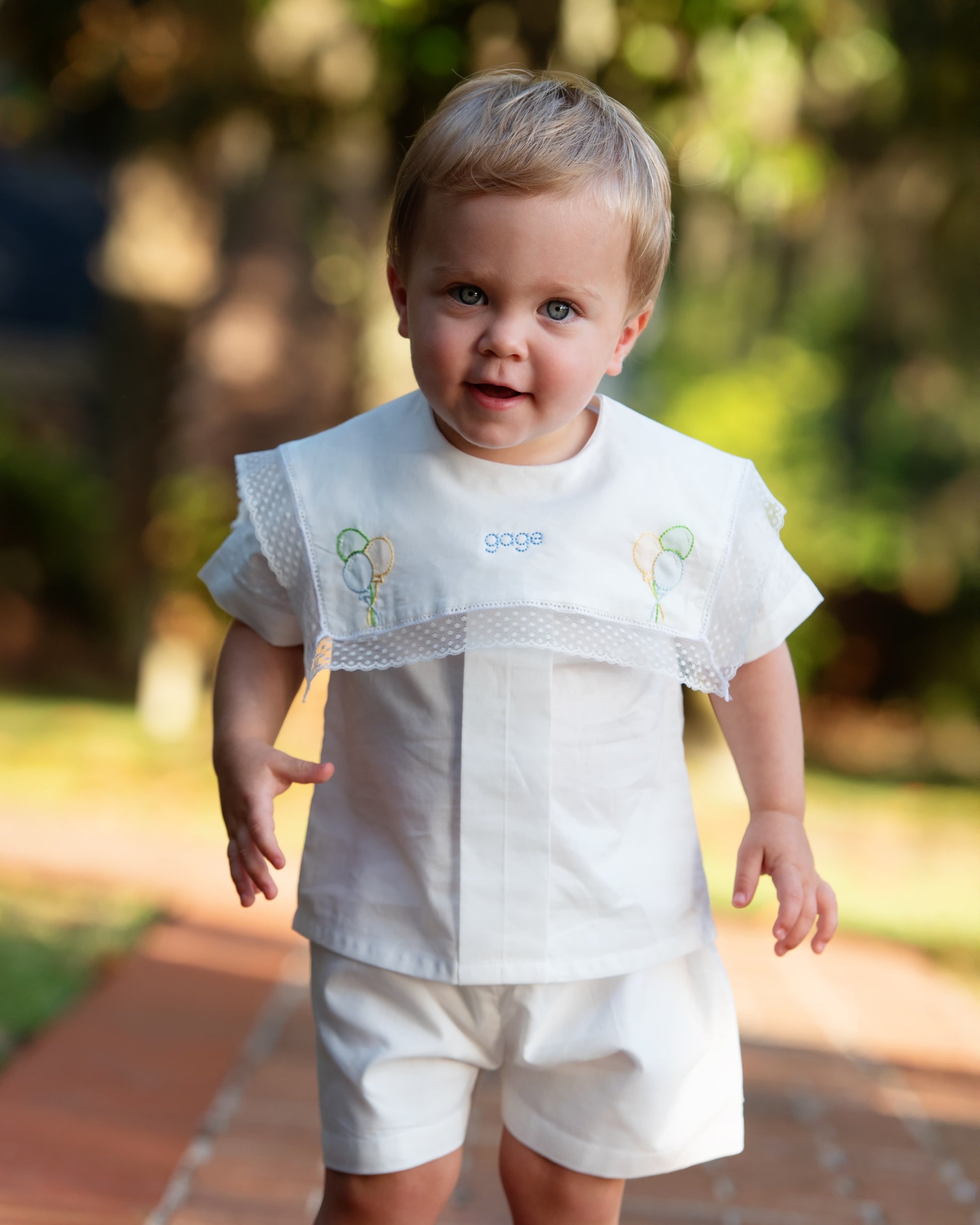 Child wearing a white outfit with lace details outdoors
