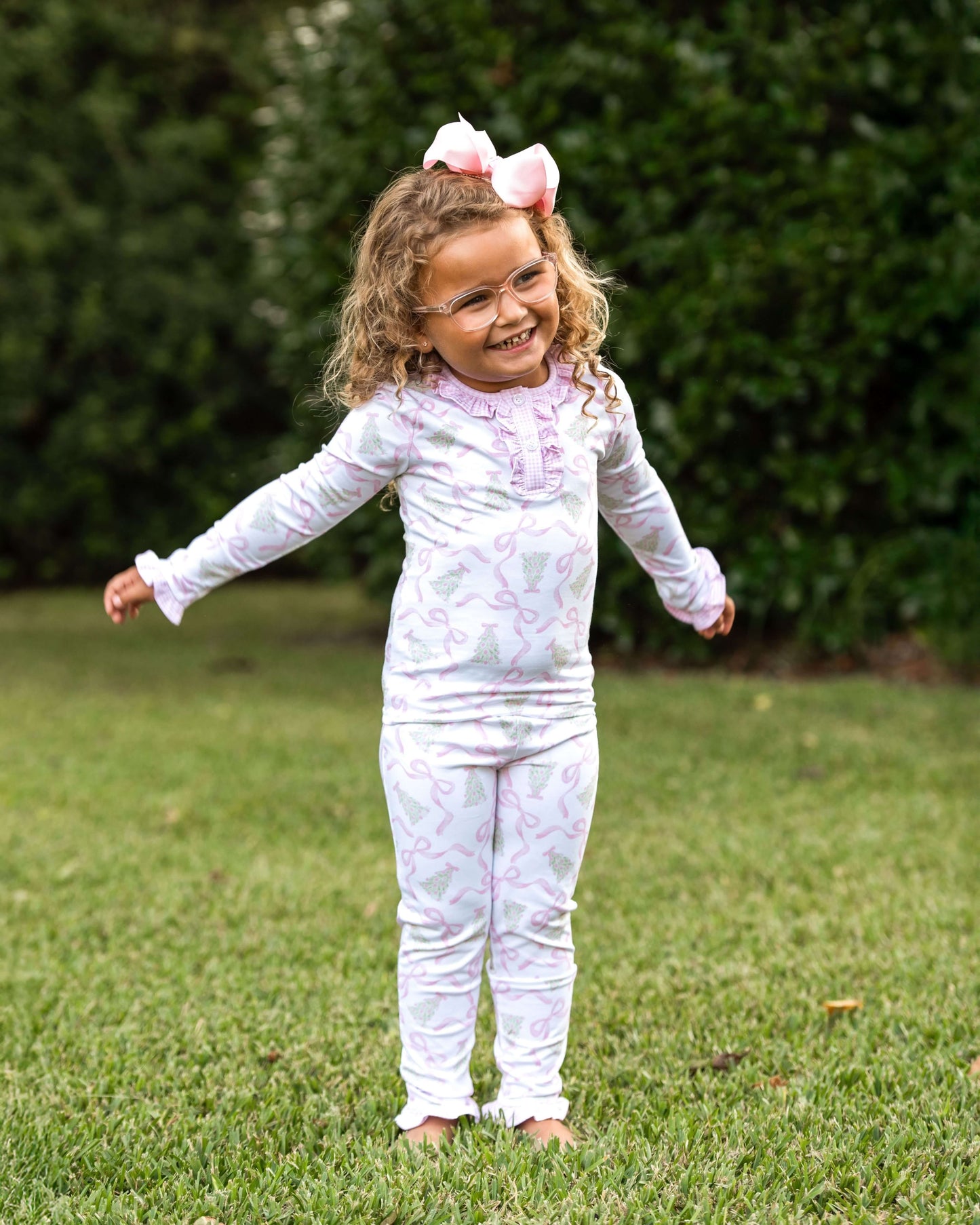 Child wearing a white outfit with pink floral patterns outdoors on grass