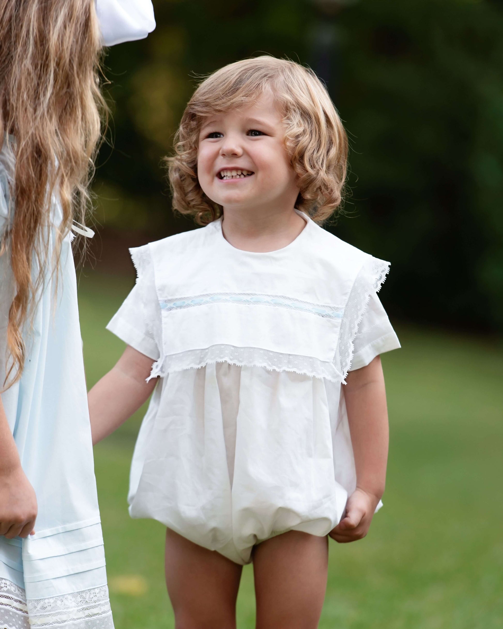 Child wearing a white outfit with ruffled details outdoors