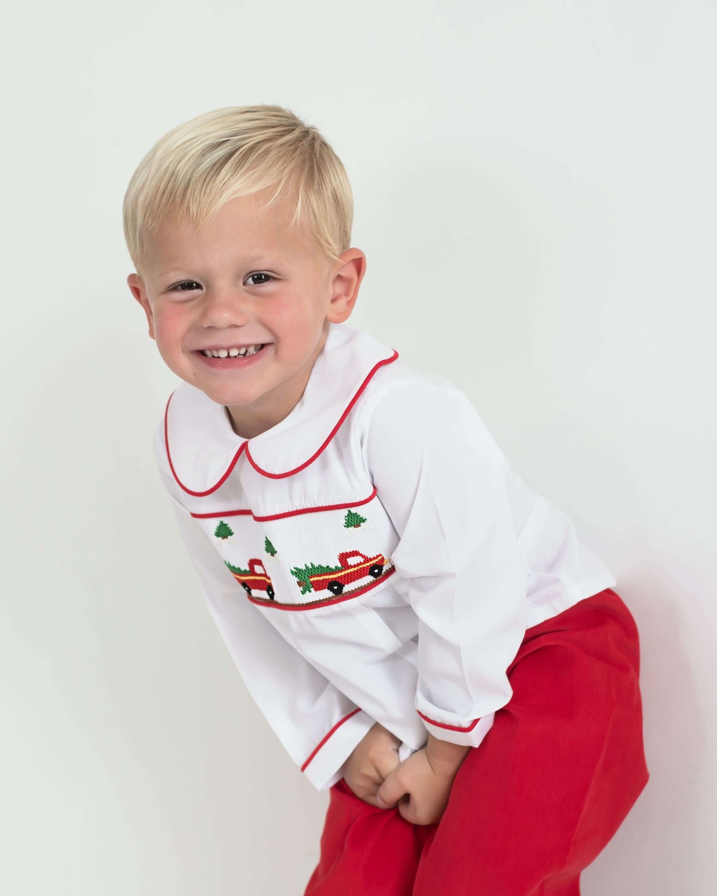 Child wearing a white shirt with red trim and red pants on a white background