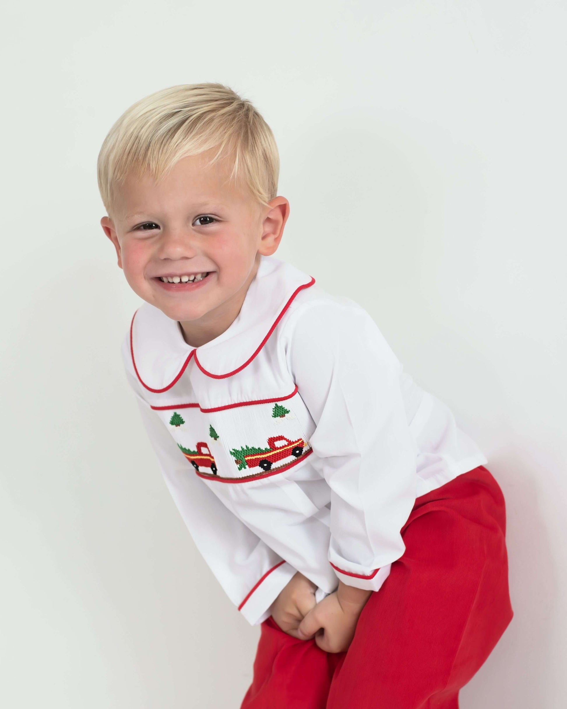 Child wearing a white shirt with red trim and red pants on a white background