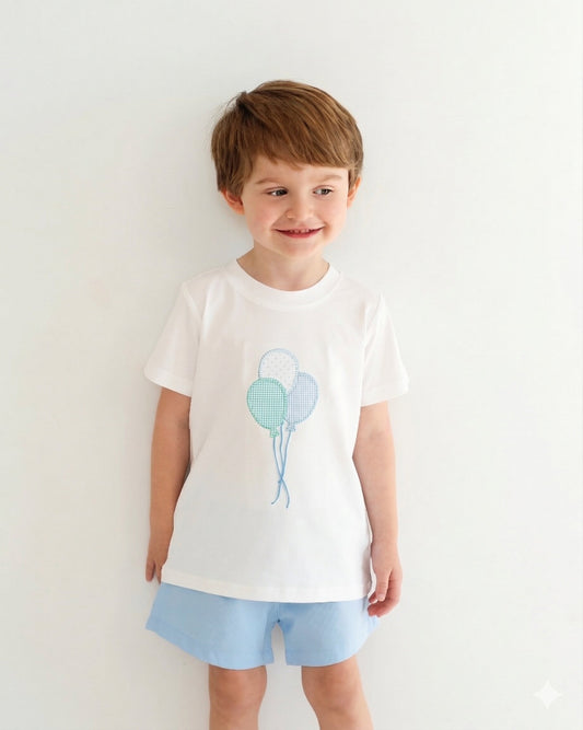 Child wearing a white t-shirt with balloon design and light blue shorts on a white background