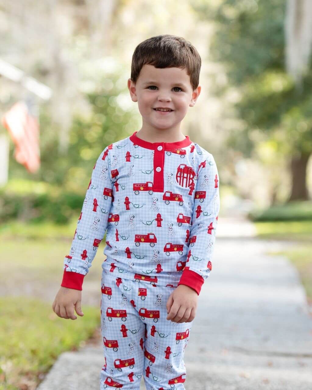 Child wearing pajamas with fire truck pattern outdoors