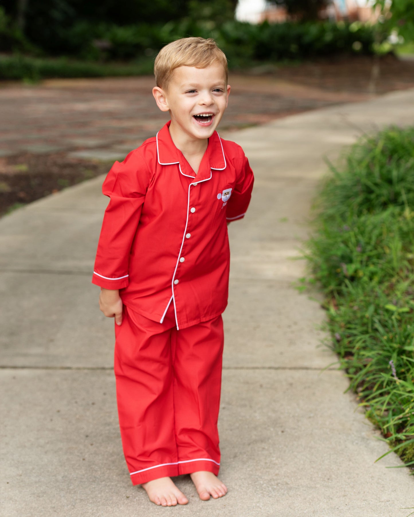 Child wearing red pajamas standing on a sidewalk