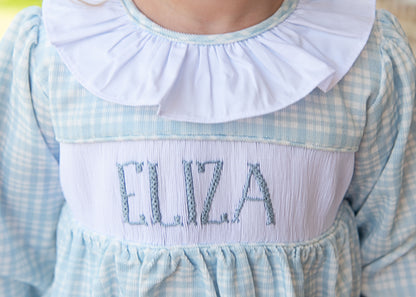 Children's dress with 'Eliza' embroidered on the chest, featuring a blue and white checkered pattern.