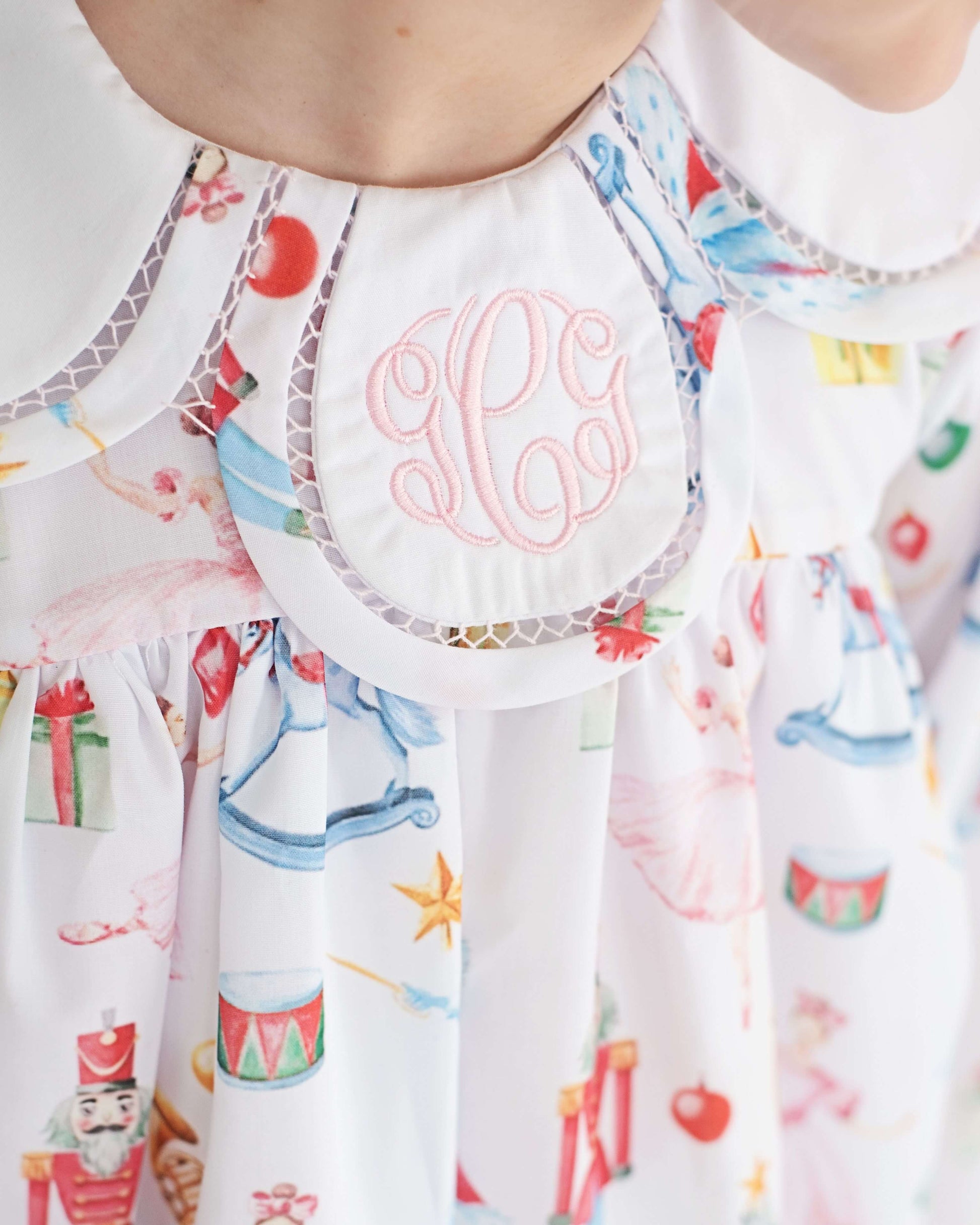 Children's dress with colorful holiday print and monogrammed initials on a white background