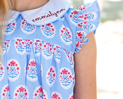 Children's dress with floral pattern and embroidered name on a blurred background